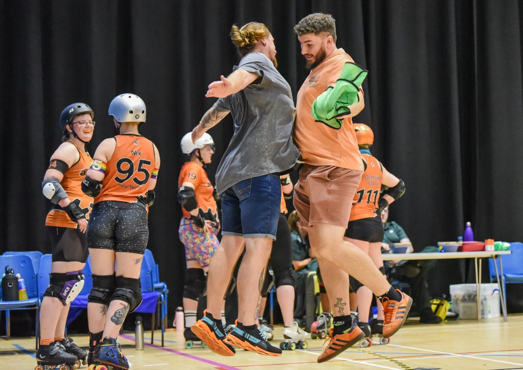 Two men, our bench coach and line-up manager, chest bump in celebration of some awesome derby shenanigans