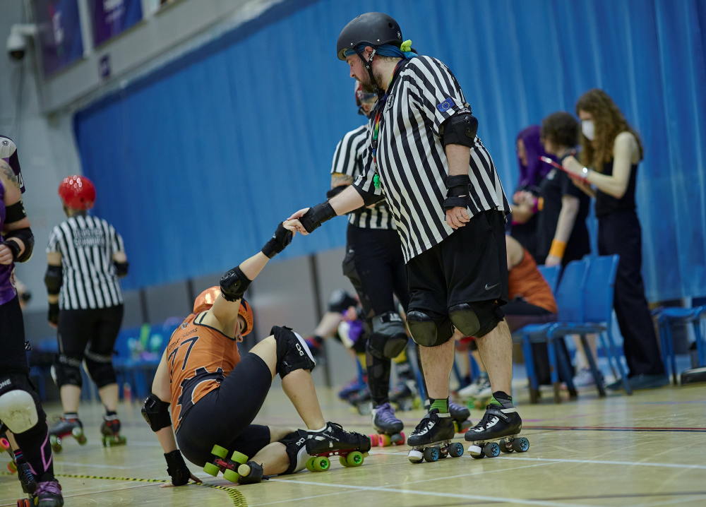 A wonderful ref, Big Whoop, provding a helping hand to an SSRD skater, Comic Slams, who had fallen over