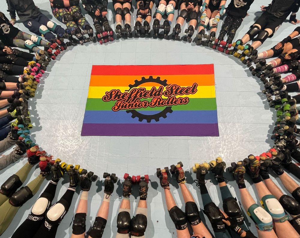 A pride flag with 'Sheffield Steel Junior Rollers' is centre, surrounded by many many sets of skaters